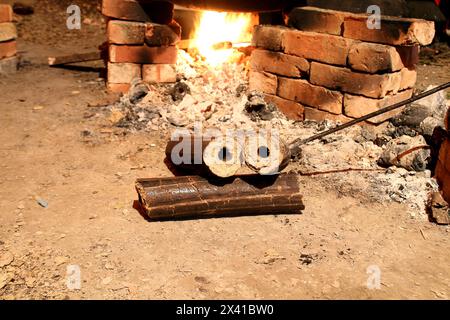 Charbons de bois, combustible solide renouvelable fabriqué à partir de la balle de riz. Cuisiner dans une fête de village sur un four temporaire en briques avec du combustible de briquette Rice Husk. Agro-RES Banque D'Images