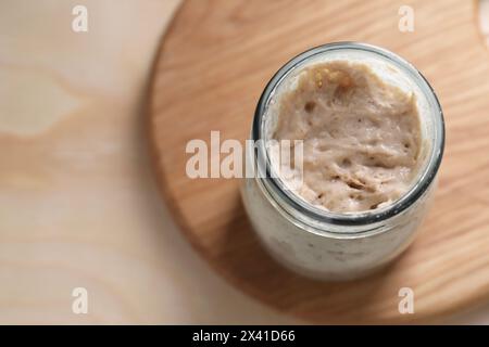 Levain de levain dans un pot en verre sur une table en bois, vue de dessus. Espace pour le texte Banque D'Images