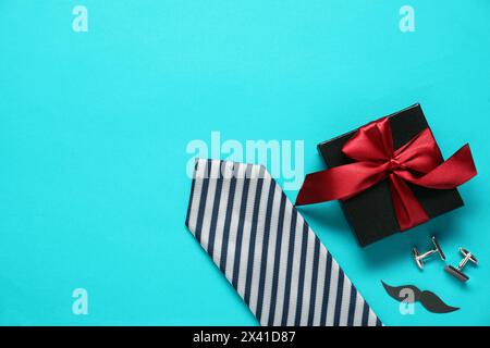 Boîte cadeau, boutons de manchette, cravate et moustache en papier sur fond bleu clair, plat avec espace pour le texte. Célébration de la fête des pères Banque D'Images