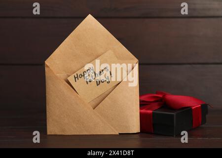 Carte avec phrase joyeuse fête des pères dans l'enveloppe et boîte cadeau sur la table en bois, gros plan Banque D'Images