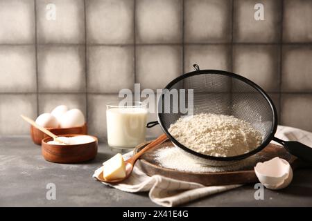 Faire de la pâte. Farine au tamis, cuillère et beurre sur table grise, gros plan Banque D'Images