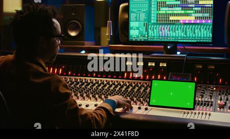 Ingénieur du son expert enregistrant des pistes audio à côté de la maquette de tablette, ajoutant des effets sonores sur les chansons avec console de mixage. Producteur appuyant sur les boutons et les curseurs dans la salle de contrôle. Caméra B. Banque D'Images