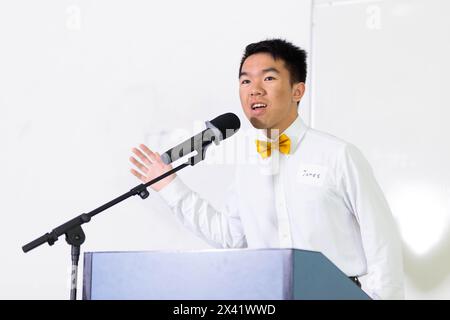 Un jeune homme fait des gestes tout en prononçant un discours sur un podium avec un microphone. Il prend la parole lors d'une conférence. Il est conférencier invité à an Banque D'Images