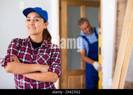 Portrait d'une jeune femme latine souriant à la caméra avec les mains croisées sur la poitrine pendant la rénovation à la maison Banque D'Images