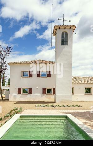 Une maison de campagne andalouse de style cortijo avec une tour de guet et une piscine de loisirs au pied Banque D'Images