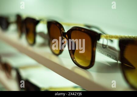 Étagères de devanture de diverses lunettes de soleil modernes dans le magasin de détail. Présentoir plein de lunettes de soleil. Lunettes de soleil à la mode, lunettes d'été sur Banque D'Images