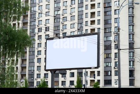 Panneau publicitaire blanc vierge près des bâtiments résidentiels dans la ville un jour d'été Banque D'Images