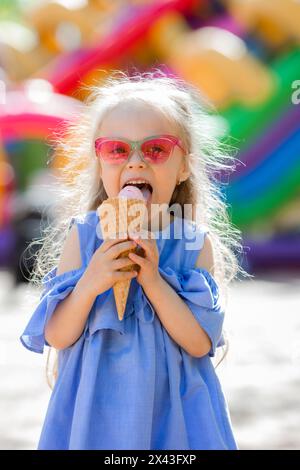 petite fille heureuse mange de la crème glacée dans le parc en été. Photo de haute qualité Banque D'Images