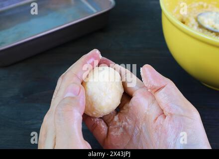 Mains façonnant la pâte pour la cuisson du pain au fromage brésilien appelé Pao de Queijo Banque D'Images