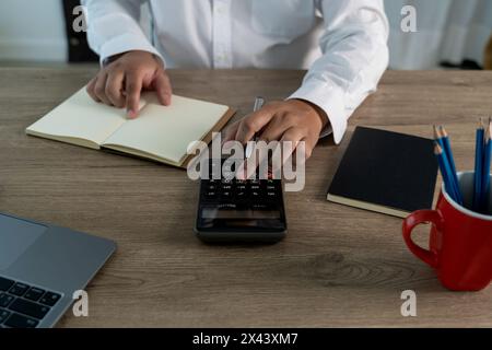 Gros plan homme d'affaires utilisant la calculatrice sur les documents l'utilisation de la finance non reconnaissable calculer au sujet du coût au bureau Banque D'Images