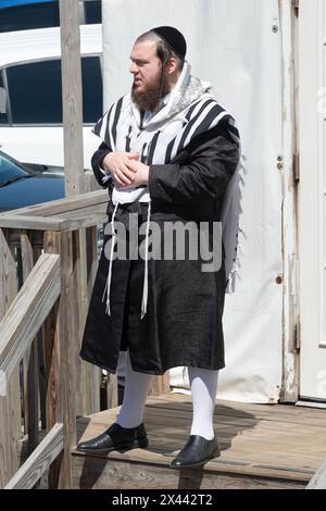 Un homme juif orthodoxe portant un châle de prière tallis et des chaussettes blanches hogh à l'extérieur d'une synagogue à la Pâque. À Monsey, comté de Rockland, New York. Banque D'Images