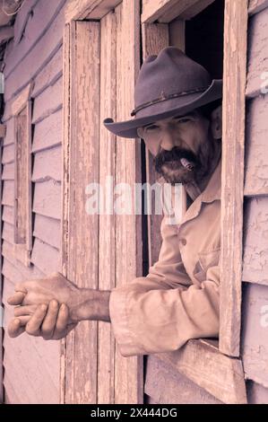 Une image infrarouge d'un producteur de tabac portant un chapeau de cow-boy fumant un cigare près de la fenêtre de sa ferme dans la vallée de Vinales, Vinales, Cuba Banque D'Images