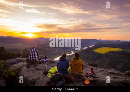 Sächsische Schweiz Sonnenaufgang auf dem Lilienstein. Der Lilienstein ist der markanteste und bekannteste Felsen im Elbsandsteingebirge. Blick ins Elbtal nach Bad Schandau. Touristen und Touristinnen geniessen ein Sonnenaufgangsfrühstürck hoch über der Elbe. Ebenheit Sachsen Deutschland *** Suisse saxonne lever du soleil sur le Lilienstein le Lilienstein est le rocher le plus frappant et le plus connu dans les montagnes de grès de l'Elbe vue sur la vallée de l'Elbe à Bad Schandau touristes profiter d'un lever de soleil petit déjeuner au-dessus de l'Elbe Ebenheit Saxe Allemagne Banque D'Images