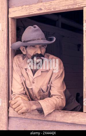 Une image infrarouge d'un producteur de tabac portant un chapeau de cow-boy fumant un cigare près de la fenêtre de sa ferme dans la vallée de Vinales, Vinales, Cuba Banque D'Images