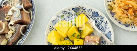 Délicieux dîners de poisson copieux, pommes de terre bouillies avec hareng mariné, choucroute avec oignons et huile d'olive, vue de dessus, bannière Banque D'Images