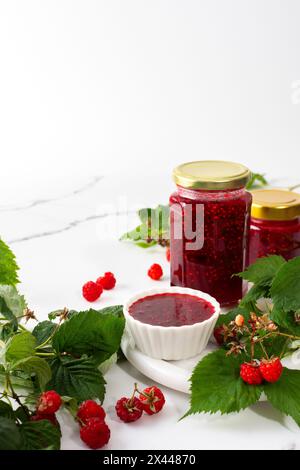 Conservation estivale maison, confiture de framboises dans des bocaux, bocaux avec confiture et brins de framboise Banque D'Images