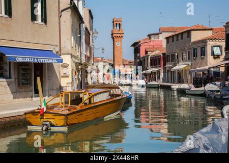 Bateaux amarrés sur le canal avec des bâtiments résidentiels colorés, maisons, magasins, touristes et tour de l'horloge sur la place San Stefano, île de Murano, Venise Banque D'Images