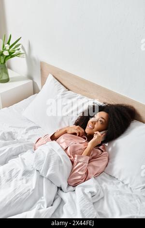 Une poupée repose paisiblement sur un lit soigneusement fait avec des draps blancs, ajoutant une touche de fantaisie au cadre confortable de la chambre. Banque D'Images