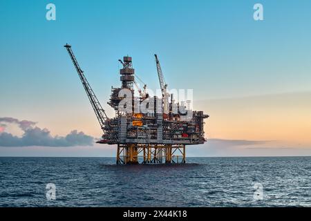 Plate-forme offshore de jackup de pétrole et de gaz dans l'océan pendant un magnifique coucher de soleil coloré. Banque D'Images