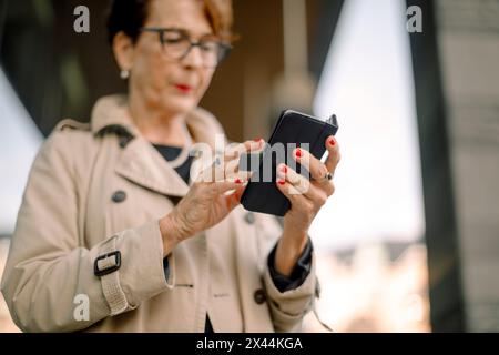 Vue à angle bas de la femme âgée retraitée à l'aide d'un téléphone intelligent Banque D'Images