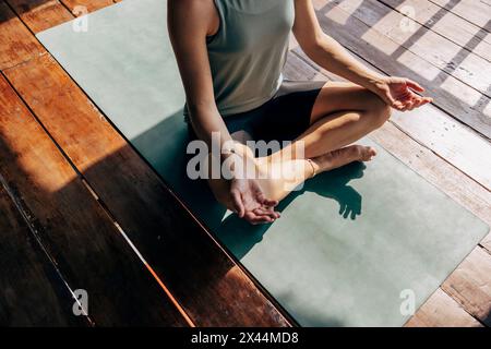 Section basse de la femme pratiquant le yoga tout en étant assis sur le tapis d'exercice à la station de bien-être Banque D'Images