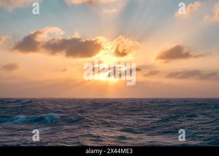 Le soleil brille à travers les nuages créant des faisceaux de lumière dans le ciel à l'horizon. Banque D'Images