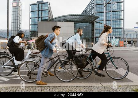 Hommes et femmes professionnels des affaires se déplaçant à travers des cycles sur la voie dans la ville Banque D'Images