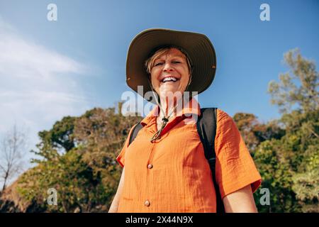 Portrait à angle bas de femme âgée souriante portant un chapeau tout en se tenant debout contre le ciel en vacances Banque D'Images
