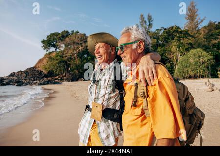 Heureux couple gay senior debout avec les bras autour et regardant la mer sur la plage Banque D'Images