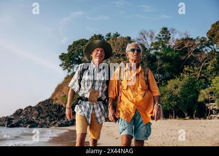 Couple gay senior marchant ensemble à la plage en vacances Banque D'Images