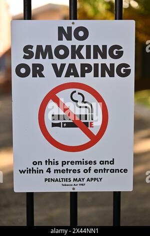 Panneau blanc, rouge et noir pour ne pas fumer ou vapoter, avec icône de cigarette et de vape, attaché à des barres métalliques Banque D'Images