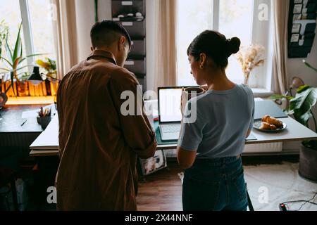 Vue arrière de la stratégie de planification des freelances hommes et femmes debout près du bureau au bureau à domicile Banque D'Images