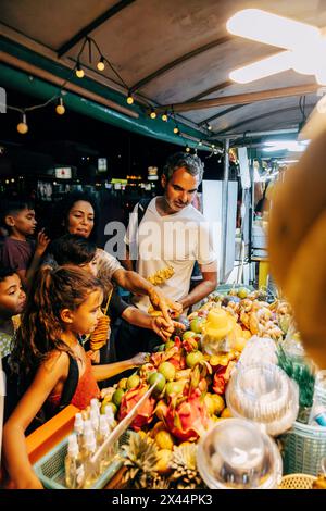 Famille touristique choisissant des fruits de l'étal au marché alimentaire Banque D'Images