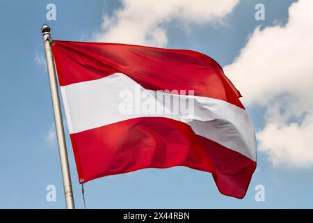 Drapeau de l'Autriche agitant dans le vent sur mât de drapeau contre le ciel avec des nuages le jour ensoleillé, gros plan Banque D'Images
