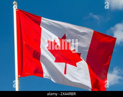 Drapeau du Canada agitant dans le vent sur mât de drapeau contre le ciel avec des nuages le jour ensoleillé, gros plan Banque D'Images