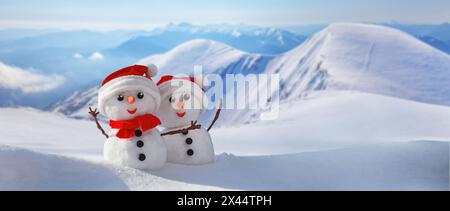 Bannière d'hiver de Noël avec un couple de bonhommes de neige dans un chapeau de père noël sur leurs têtes contre la toile de fond des montagnes enneigées. Arrière-plan congé avec copie sp Banque D'Images