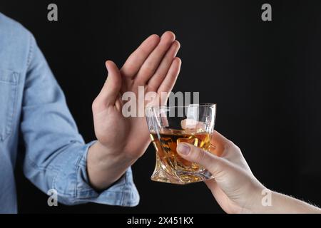 Alcoolisme. Homme refusant le verre de whisky sur fond sombre, gros plan Banque D'Images