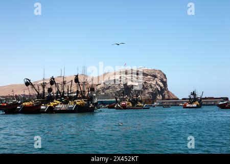 Chalutiers de pêche noirs chargés de matériel amarré dans le port, promontoire El Morro en arrière-plan, Arica, Chili Banque D'Images