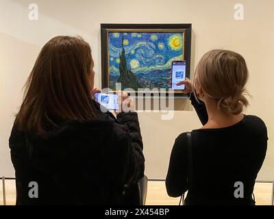 Deux personnes prennent en photo la nuit étoilée (nom original de sterrennacht) de Vincent Van Gogh à l'intérieur du musée d'art MOMA à New York, le 19 novembre 2023 Banque D'Images