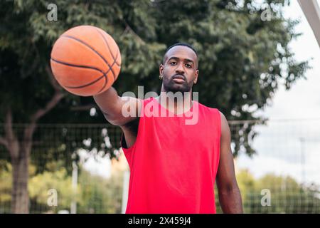 Portrait d'un joueur de basket-ball masculin sur le terrain. Il tient le basket avec confiance Banque D'Images