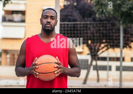 Portrait d'un joueur de basket-ball masculin sur le terrain. Il tient le basket avec confiance Banque D'Images