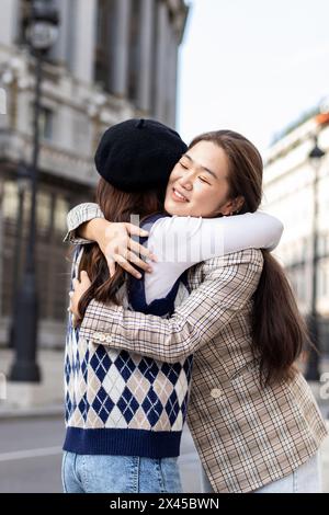 Deux amies asiatiques se rencontrant et se serrant dans la rue de la ville Banque D'Images