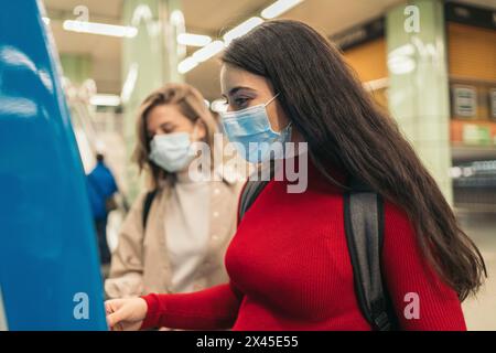 filles achetant un billet pour métro avec masque Banque D'Images