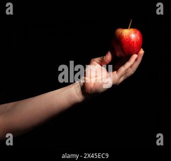 pomme en main sur fond noir Banque D'Images