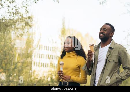 un couple de noirs qui mange de la crème glacée dans un parc Banque D'Images