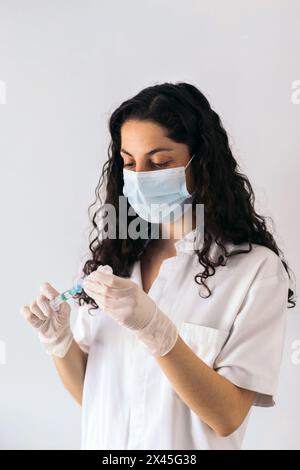 portrait d'infirmière avec masque injectant du sérum dans une seringue Banque D'Images