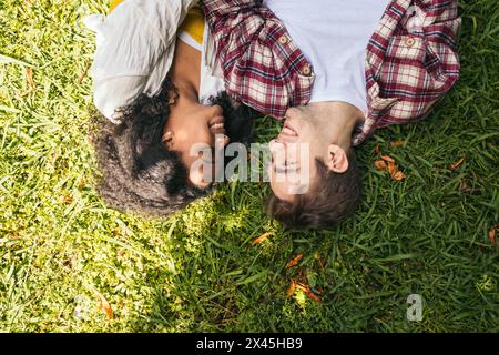 Vue aérienne d'un jeune couple interracial allongé sur l'herbe dans le parc Banque D'Images