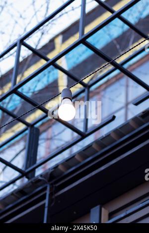 Une chaîne de lumières est suspendue à une poutre en bois robuste, ajoutant une ambiance chaleureuse à la zone ombragée ci-dessous. La structure en bois dur est accentuée avec WO Banque D'Images