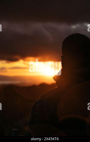 Homme méconnaissable regardant un beau coucher de soleil dans la campagne au Costa Rica. Le soleil se couche sur les montagnes Banque D'Images