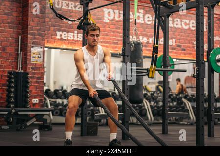 homme athlète s'entraîner avec les cordes dans une salle de gym Banque D'Images